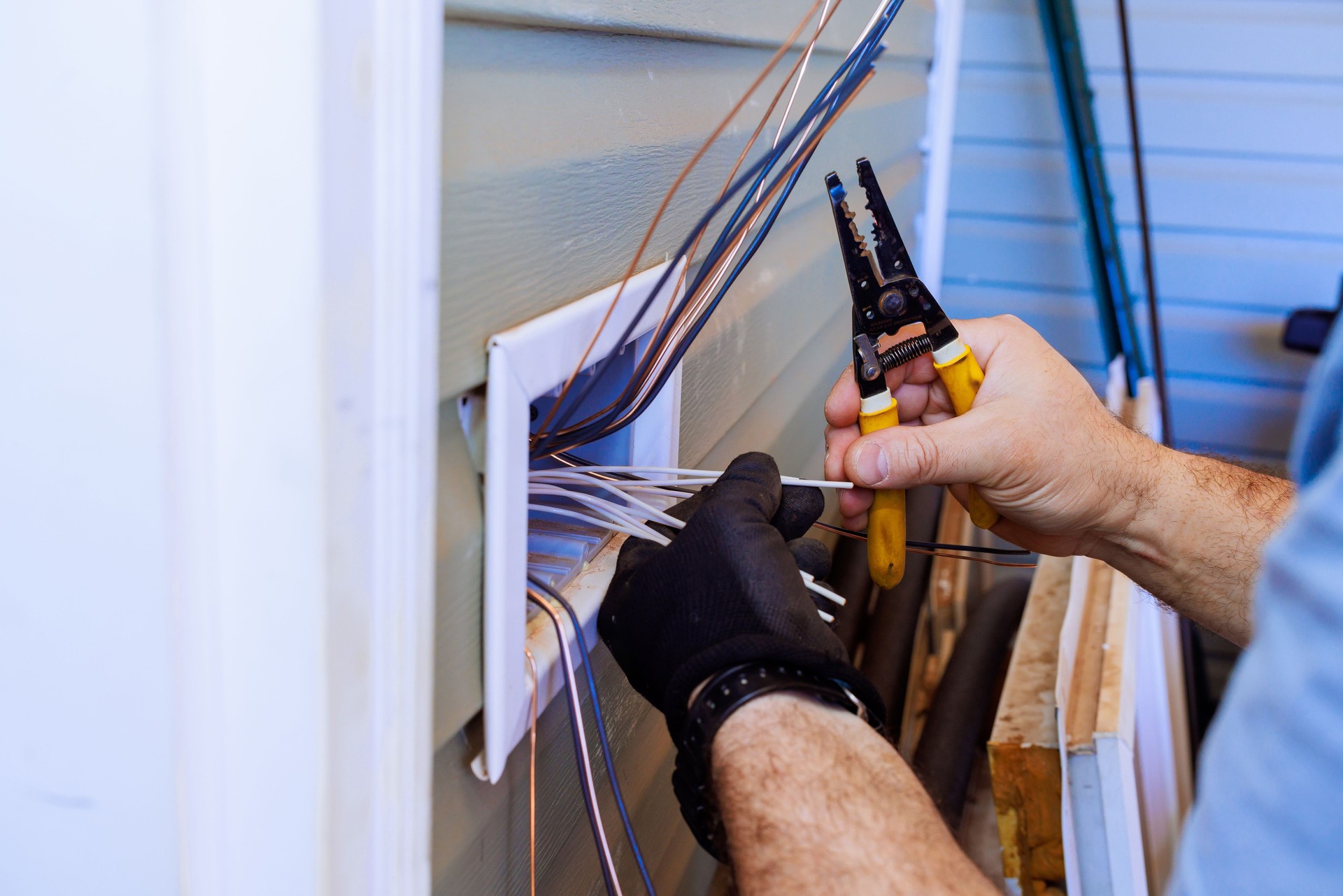 Expert technician working on electrical wiring near a residential home in a clear afternoon light